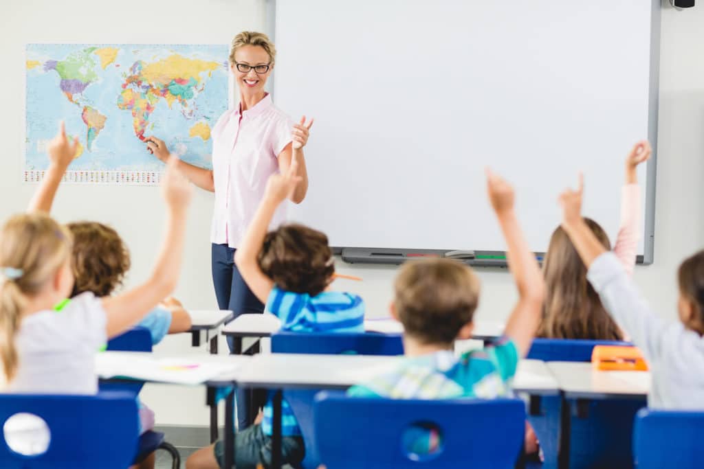 Teacher instructing in a classroom full of young students.