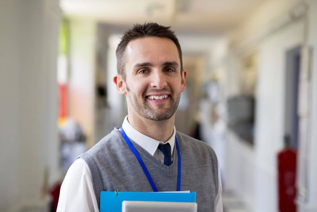 Smiling teacher standing in a hallway.