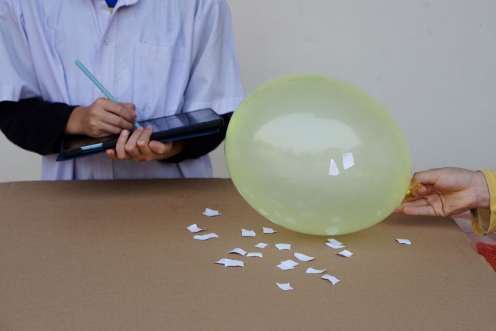 A student does a science experiment with a balloon and takes notes.