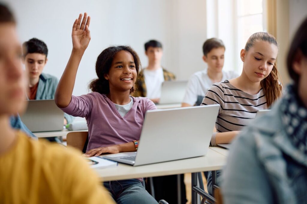A student raises her hand to ask a question in class.