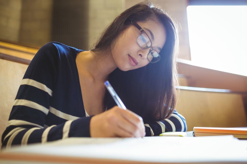 Young women taking notes while sitting at a desk.