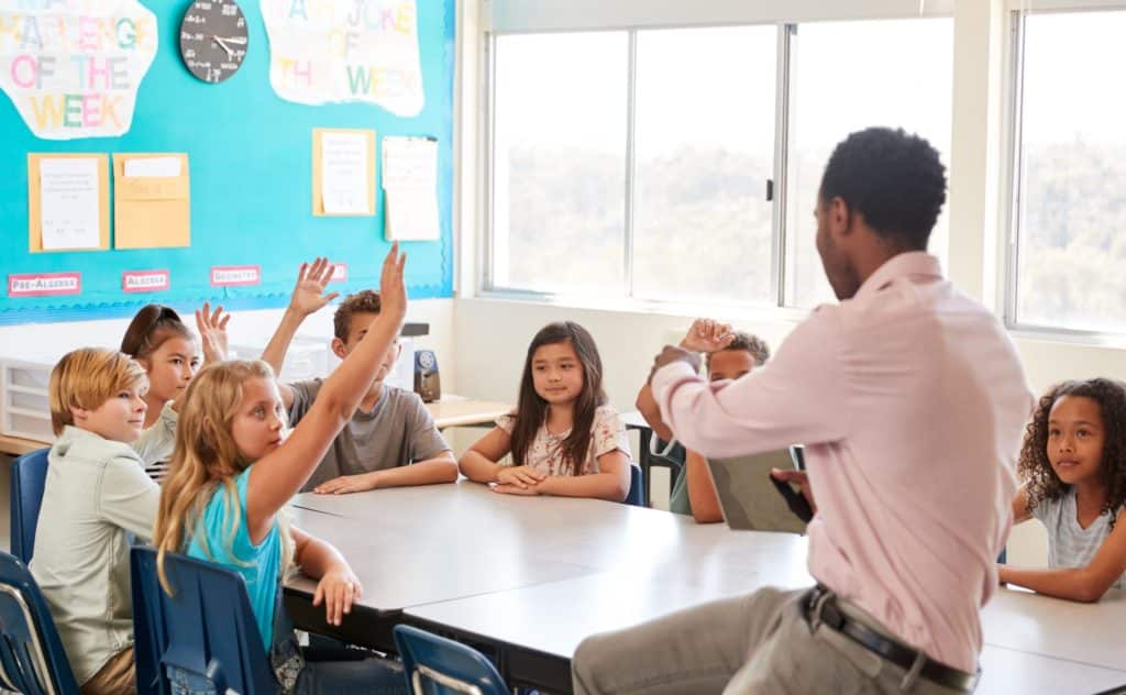 Teacher sitting with a group of students for a discussion.