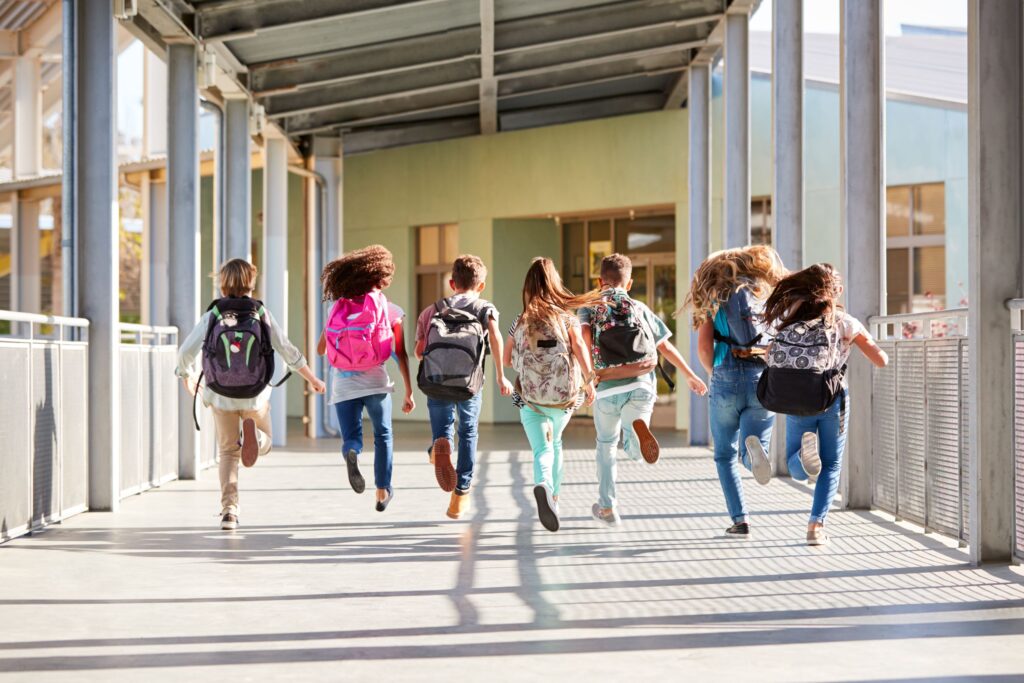 Seven students happily run toward school.