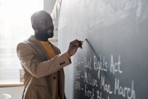 How to become a history teacher: a history teacher stands at the chalkboard, writing out lecture material.