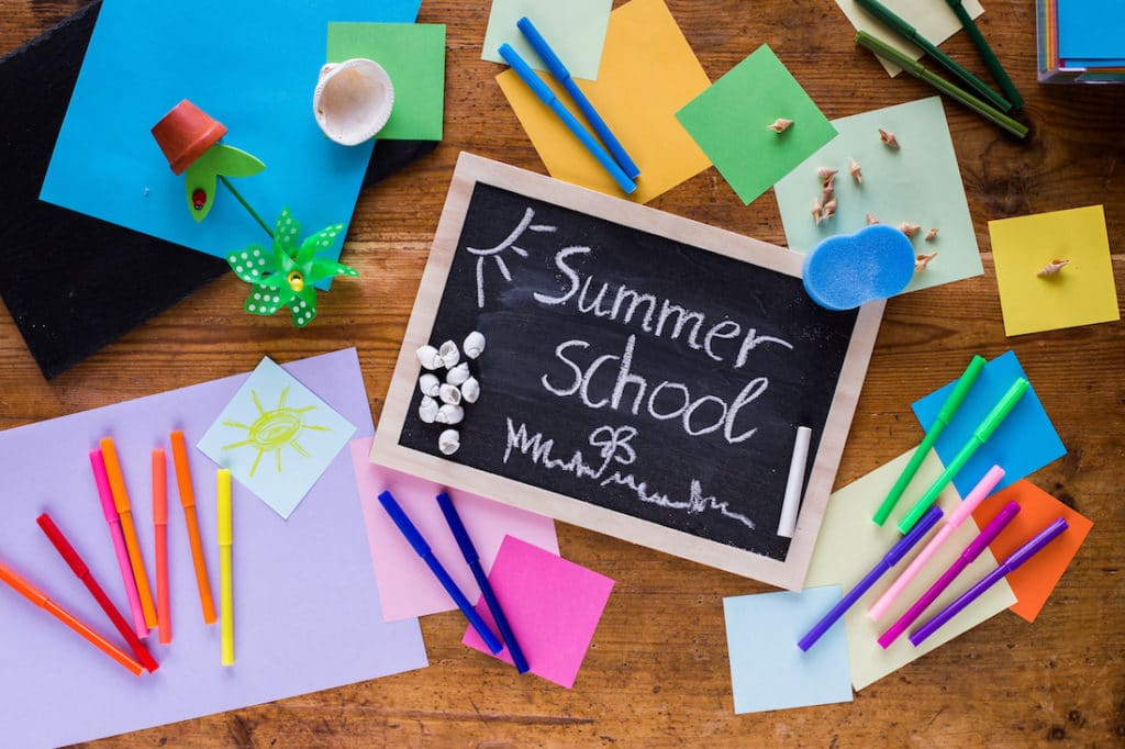 ‘Summer School’ written on a small chalkboard surrounded by craft supplies.