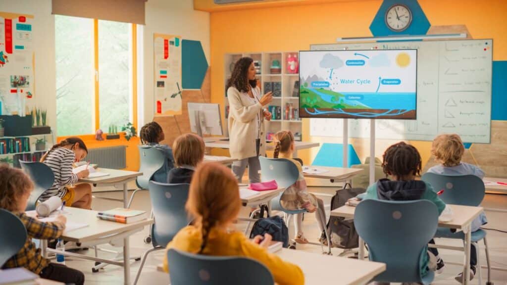 Teaching jobs; A teacher stands at the front of her classroom, teaching her students a science lesson.