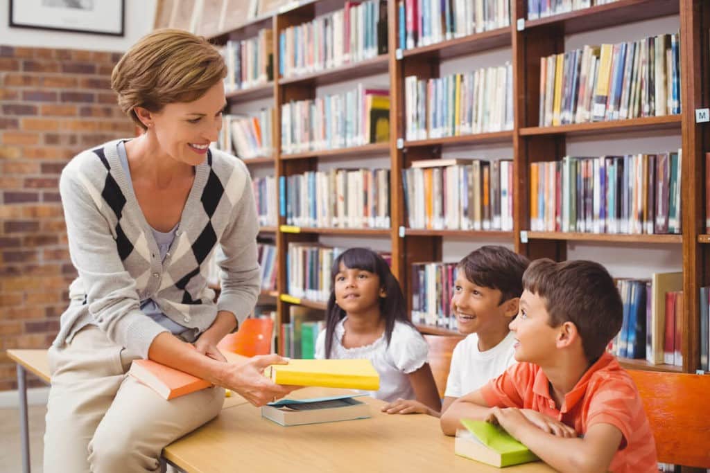 A librarian helping young students with finding books.