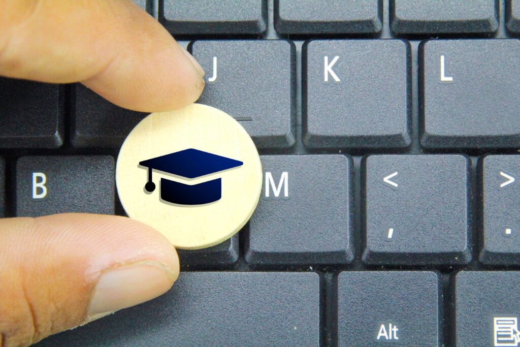 A close-up of someone holding a coin that has a graduation cap on it.