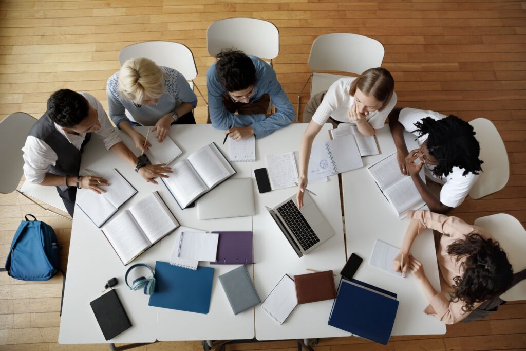 A group of students sit at a library table doing homework.