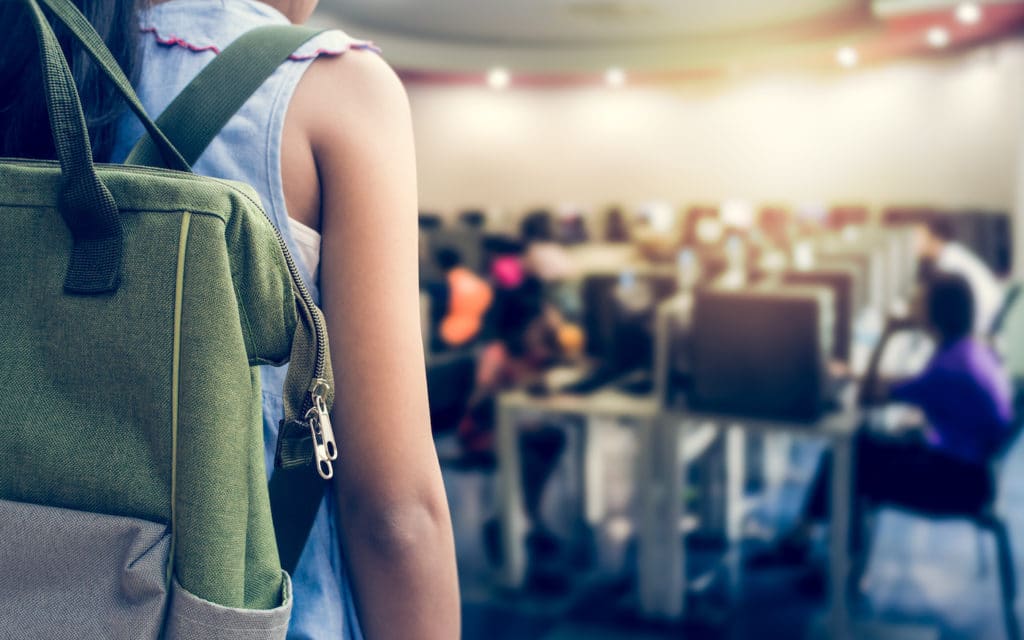 Student wearing a backpack entering a computer classroom.