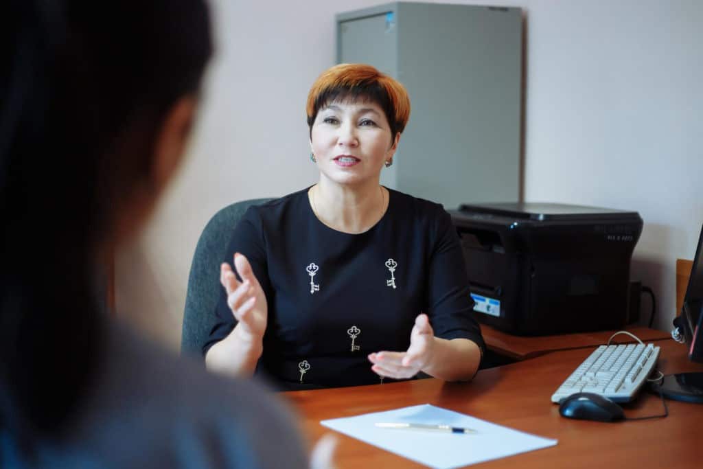 School principal at her desk across from someone.